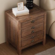 a small wooden table with two drawers and a book on top of it next to a chair