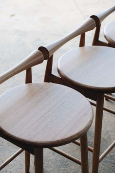 three wooden stools sitting next to each other on the cement floor in front of a building