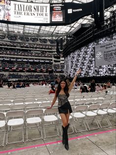 a woman standing in the middle of an empty stadium with her arms up and legs crossed