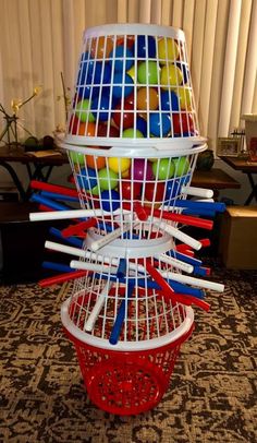 a bird cage filled with lots of different colored balls and sticks in it's bottom