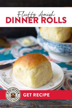 a white plate topped with a roll on top of a table next to a bowl of bread