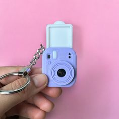 a hand holding a camera keychain with a pink and blue case on it