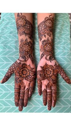 two hands with henna tattoos on them, one is showing off the intricate design