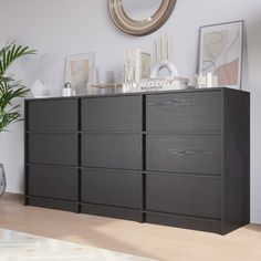 a large black dresser sitting in a living room next to a potted plant