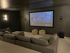 a large couch in front of a projector screen with two pillows on the back