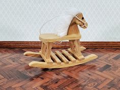 a wooden rocking horse with white feathers on it's head sitting on the floor