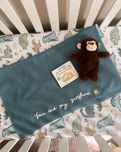 a stuffed monkey is laying on top of a crib next to a baby's book