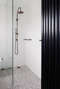 a bathroom with black and white tile flooring, a shower head, and a toilet