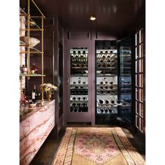 a wine cellar with many bottles and glasses on the shelves, in front of an ornate rug