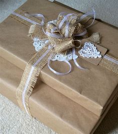 two wrapped gift boxes with lace and bows on the top are sitting on carpeted floor