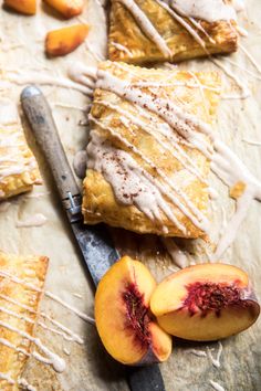 peach pastries with icing and sliced peaches on a cutting board next to a knife