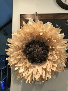 a large sunflower hanging on the wall next to a chalkboard with a clock above it