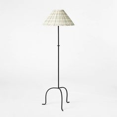 a lamp that is on top of a metal stand with a white shade over it