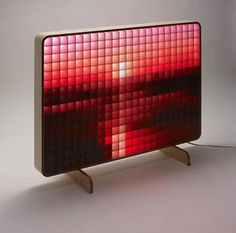 a red and black mosaic tile on a wooden stand with a white light behind it