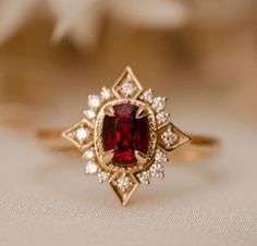 a close up of a ring with a red stone in the middle and white diamonds around it