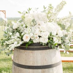 a wooden barrel with white flowers and greenery