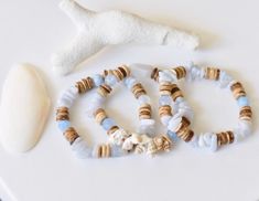 three bracelets with shells and seashells are on a table next to a white starfish ornament