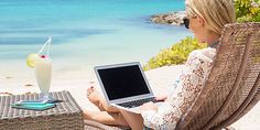 a woman sitting in a chair with a laptop on her lap looking out at the ocean