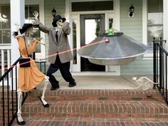 two skeletons dressed up in halloween costumes walking down the steps with a flying object behind them