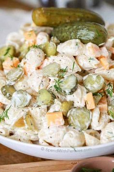 a white bowl filled with cucumber and cheese salad next to a pickle