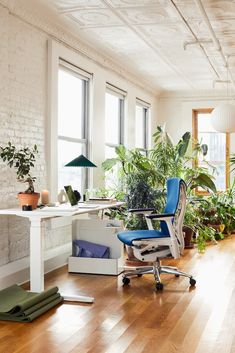 an office with lots of plants in the windows and wood flooring on the walls