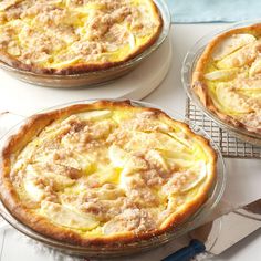 three pies sitting on top of a white table next to a knife and fork