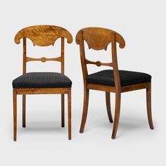 two wooden chairs with black upholstered seats and back cushions, side by side