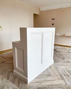 an unfinished room with white cabinets and wood flooring