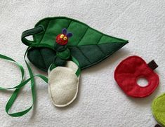 three felt toys are laying on the floor next to each other and one has a green leaf with a ladybug on it