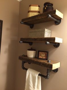 two wooden shelves holding towels and other items in a bathroom with a toilet paper dispenser on the wall