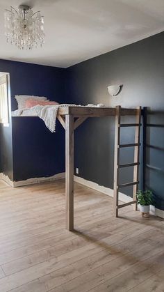 a loft bed in the middle of a room with blue walls and wood floors, along with a chandelier hanging from the ceiling