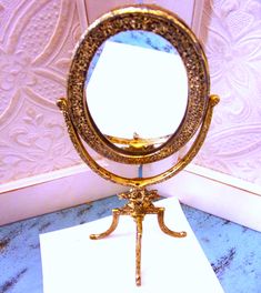 a mirror sitting on top of a table next to a white piece of paper in front of it