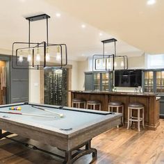 a pool table in the middle of a room with bar stools and an island