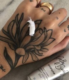 a person's hand with tattoos on it next to a tube of lotion