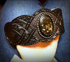 "\"Out of the dark\" is a hand tooled and hand painted leather bracelet with iridescent seraphinite cabochon. It was made to fit the 7 1/2\" (19cm) wrist. This particular cuff was MADE TO ORDER. If you would like me to design something for you welcome to place a custom order and we will discuss a design, which would match your personality. I've got plenty of different gemstones in stock, thus I believe we would find something just for you. Once the order is ready it will be shipped to you by pri Handmade Black Artisan Leather Bracelet, Handmade Artisan Black Leather Bracelet, Formal Handmade Leather Jewelry, Artisan Adjustable Black Cuff Bracelet, Custom Handmade Leather Bracelets, Unique Hand Tooled Black Jewelry, Custom Handmade Adjustable Leather Bracelet, Adjustable Hand Painted Leather Jewelry, Handmade Adjustable Leather Bracelet