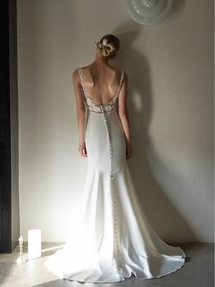 a woman in a white dress standing next to a wall with an object on it