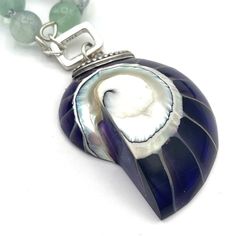 "Rainbows and mermaids are proof that imagination and beauty go hand in hand." Embrace your inner mermaid when wearing this gorgeous one of a kind gemstone pendant necklace. Hand-knotted Rainbow Fluorite gemstones in various shades of green, purple and blue reminds one of a mermaid's iridescent scales. Hanging from these genuine gem beads, is a vintage sterling silver and real nautilus shell pendant. The natural seashell is incased in purple resin to create a unique statement piece. A true treasure to add to your boho jewelry box. Real gemstone necklace composed of 8mm multicolor or rainbow Fluorite beads with a vintage sterling silver, real nautilus shell, and purple resin pendant. Approximately 28 inches in length including antique sterling silver and nautilus or ammonite shell pendant, Unique Shell Pendant Necklace As Gift, Unique Shell Pendant Necklace For Gift, Unique Pendant Shell Necklace As Gift, Unique Shell Necklace For Gift, Unique Gemstone Necklace With Mother Of Pearl, Unique Mother Of Pearl Pendant Necklaces, Unique Mother Of Pearl Pendant Necklace, Abalone Shell Necklaces With Natural Stones For Gifts, Spiritual Healing Shell Jewelry