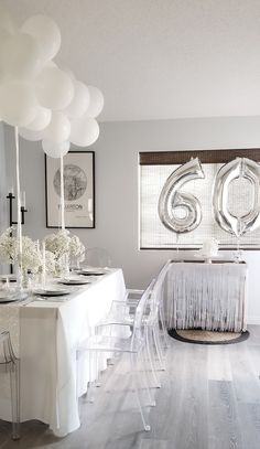 a dining room table with white balloons hanging from it's ceiling and chairs around it