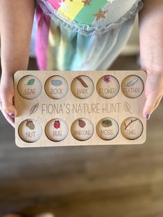 a person holding up a wooden sign that says flora's nature hunt and fruit