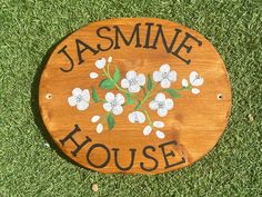 a wooden sign that says jasmine house with flowers painted on the front and side