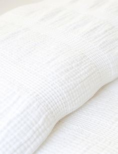 an unmade bed with white sheets and pillows