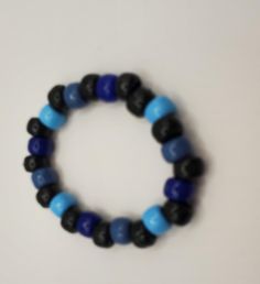 Stretchy string with black, blue and turquiose pony beads. The cord is stretchy elastic.  It measures two inches across and in length. It will fit a child or an adult. Blue Wooden Beads Bracelet, Adjustable Blue Beaded Bracelets With Wooden Beads, Blue Wooden Beaded Bracelets For Beach, Blue Wooden Bead Bracelet, Adjustable Blue Beaded Stretch Bracelet, Adjustable Beaded Blue Stretch Bracelet, Casual Blue Beaded Stretch Bracelet, Casual Blue Hand-strung Beaded Bracelets, Blue Wooden Beaded Bracelets As Gift