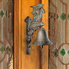 a metal bell hanging from the side of a wooden door