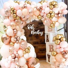 a pink and gold balloon arch with baby's name written on the front door