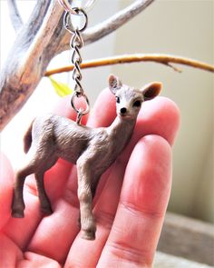 a small deer keychain is being held by someone's hand