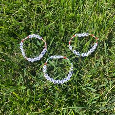 two bracelets made out of plastic beads sitting in the grass