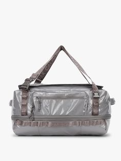 a silver duffel bag sitting on top of a white floor