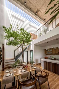 a dining room with wooden tables and chairs next to a tree in the middle of it