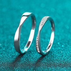 two wedding rings sitting on top of a blue surface with sparkles in the background