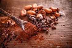 cocoa beans and powdered chocolate on wooden table with spoon closeup view from above